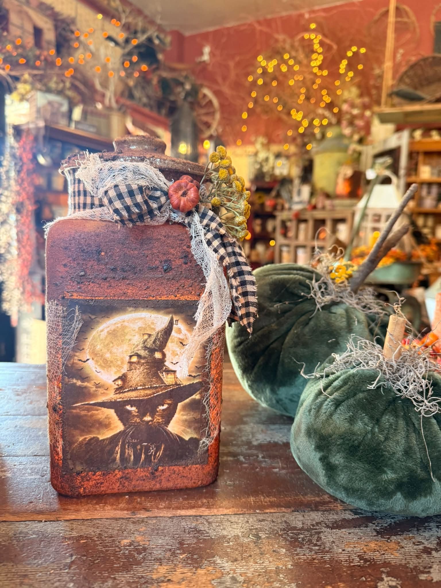 A layered home-décor vignette with a candle and velvet pumpkins