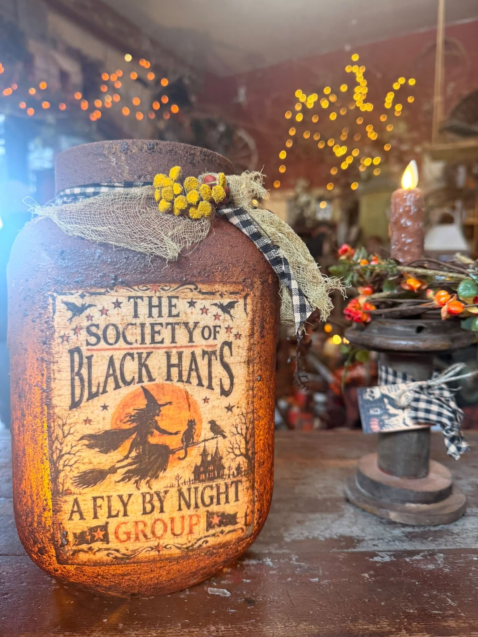 A primitive crock candle glowing with a hand-lettered folk label